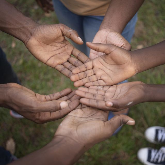 Several people holding out their open palms together in a circle.